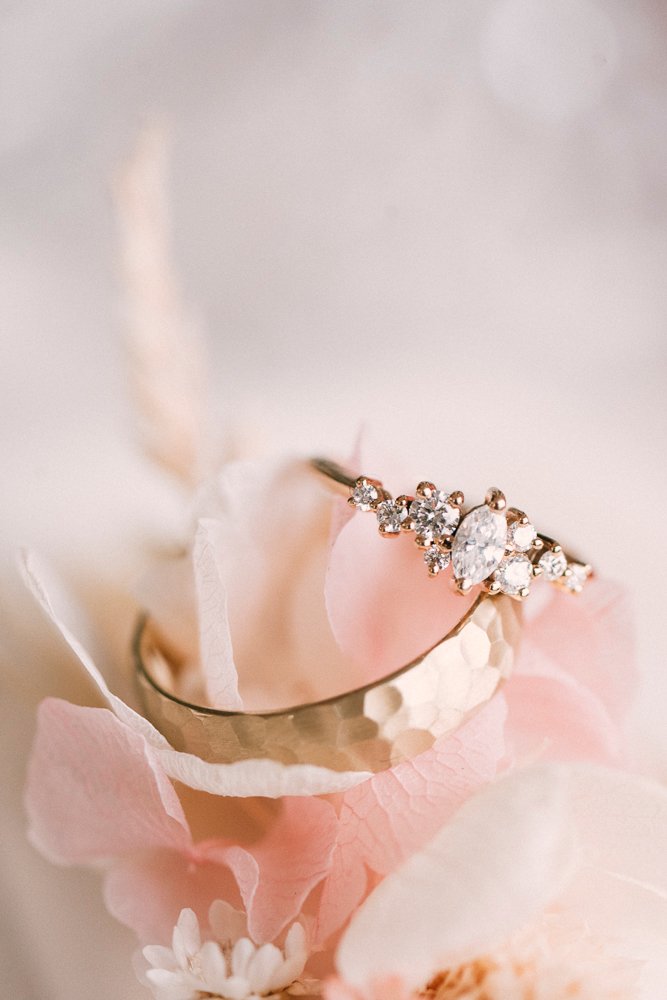 a gold ring with diamonds on a pink flower